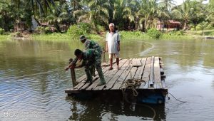 Salut, Anggota TMMD Ini Bantu Warga Seberangi Sungai dengan Rakit