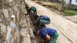Anggota Satgas TMMD 110 Kodim 1201 Bersihkan Saluran Pembuangan Air Warga