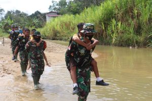 Prajurit TNI Ini Bantu Anak-anak Sekolah Menyeberangi Sungai Di Saat Kegiatan TMMD ke-110