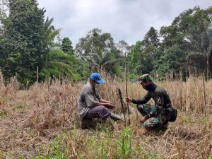 Anggota Satgas TMMD Ke 110 Bantu Warga Bersihkan Rumput Di Kebun